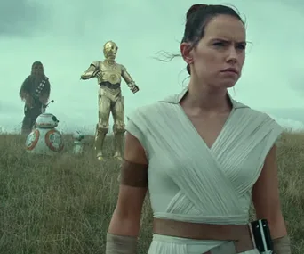 Rey stands in a grassy field with Chewbacca, BB-8, C-3PO, and D-O, from Star Wars: Episode IX - The Rise of Skywalker.