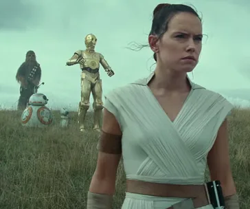 Rey stands in a grassy field with Chewbacca, BB-8, C-3PO, and D-O, from Star Wars: Episode IX - The Rise of Skywalker.