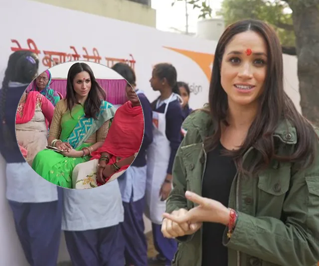 A woman with a bindi and green sari, in India, speaking with a group of women.