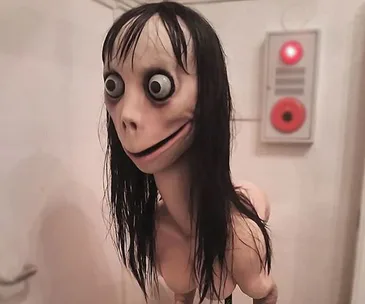 Creepy sculpture with wide eyes, long black hair, and a haunting smile, standing in front of a wall control panel.