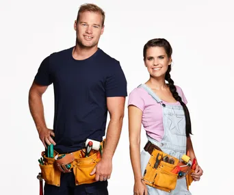 A man and woman in casual work clothes, wearing tool belts, standing confidently against a white background.