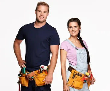 A man and woman in casual work clothes, wearing tool belts, standing confidently against a white background.