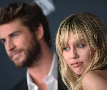 A blonde woman and a bearded man in formal attire, attending a public event.