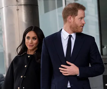 Prince Harry and Meghan Markle walk side by side, dressed in formal attire.