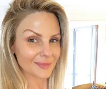 Smiling person with blonde hair and clear skin in a bright room.