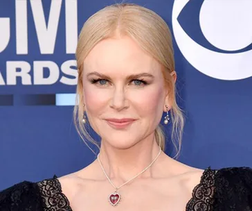 Alt text: "Person with blonde hair in formal attire, smiling at an awards event."