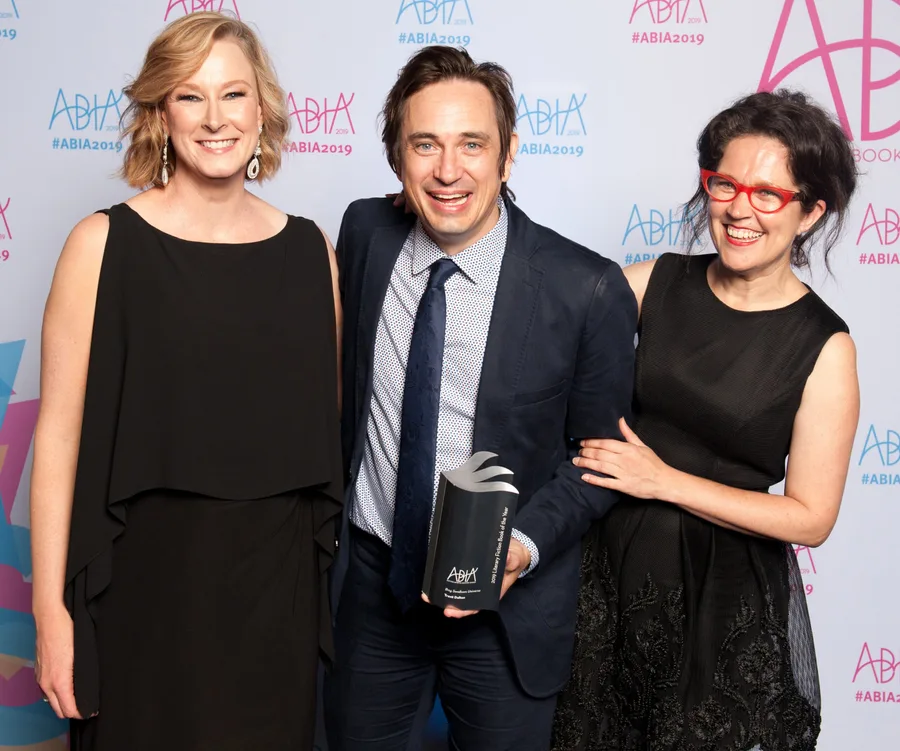 Three people smiling at the 2019 Australian Book Industry Awards, holding an award trophy.
