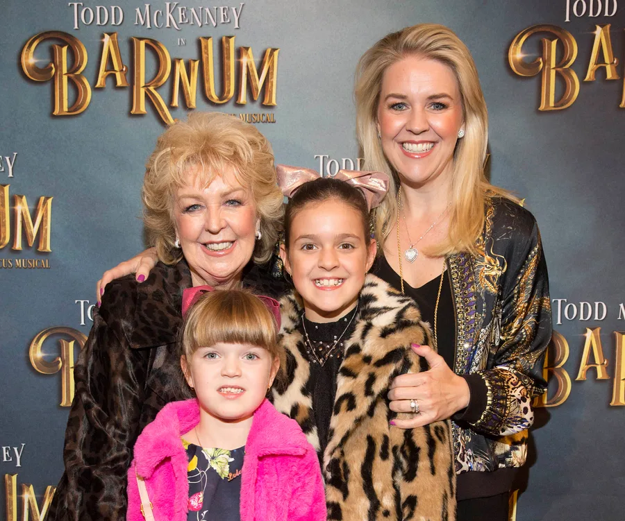 Group at 'Barnum' musical premiere, smiling for a photo with the event's backdrop.