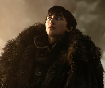 Bran Stark from Game of Thrones looks upwards, wearing a fur cloak with glowing eyes, shrouded in misty surroundings.