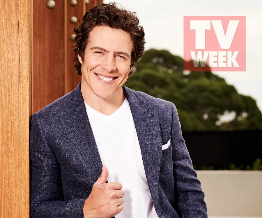 Man in a blue blazer smiling and giving a thumbs up, with a "TV WEEK" logo in the background.
