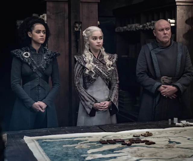 Three characters from Game of Thrones stand by a table with a map in a strategic planning scene.