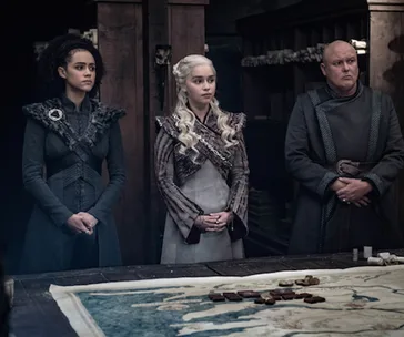 Three characters from Game of Thrones stand by a table with a map in a strategic planning scene.
