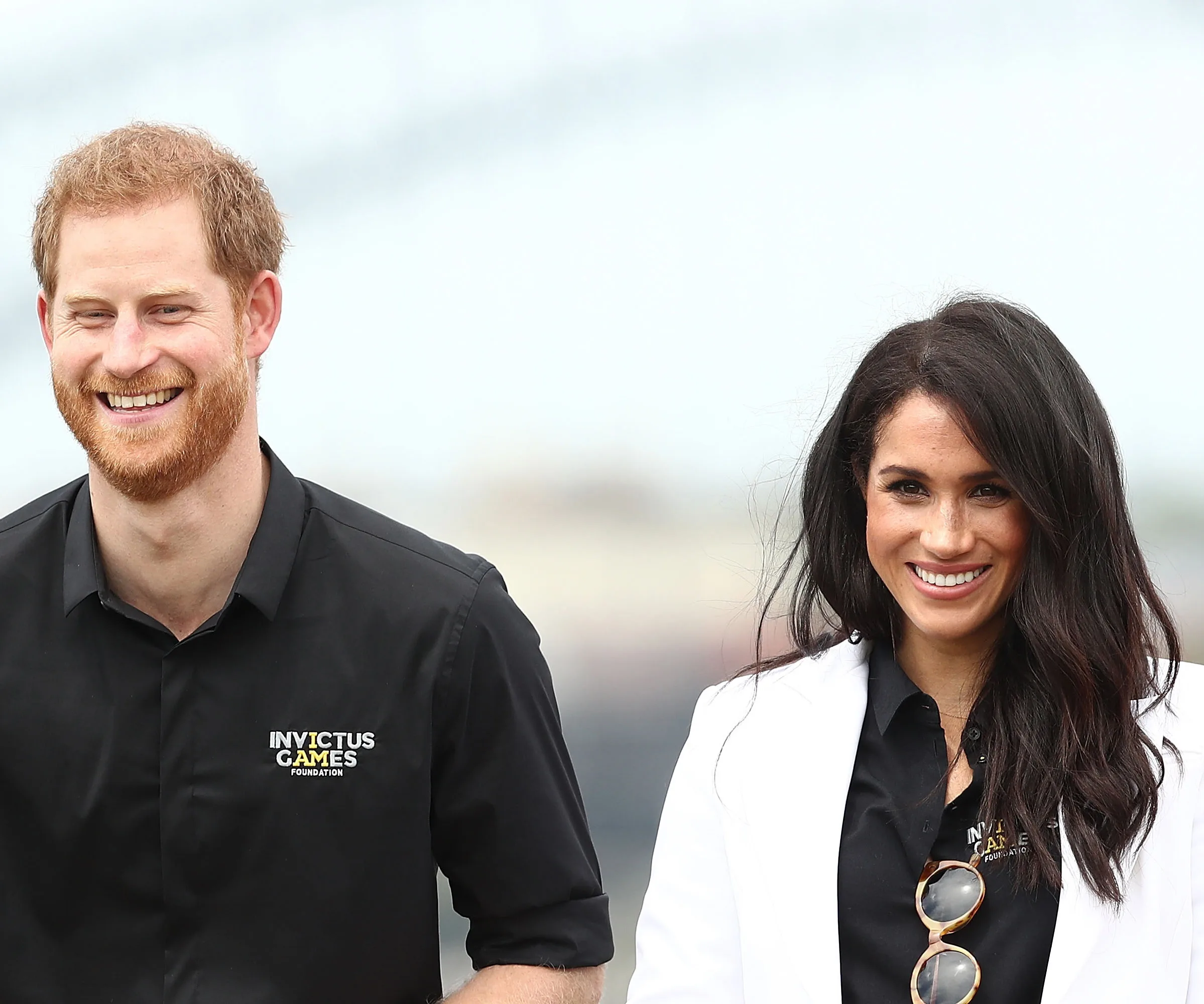 A smiling man and woman in matching Invictus Games apparel, standing outdoors.
