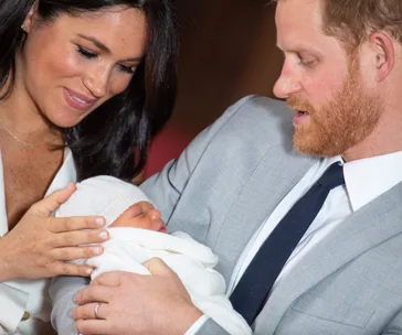 "New parents lovingly gaze at their newborn wrapped in a white blanket."