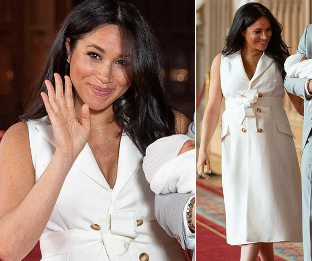 Meghan Markle in a white dress, smiling and holding a newborn, likely during a public appearance.