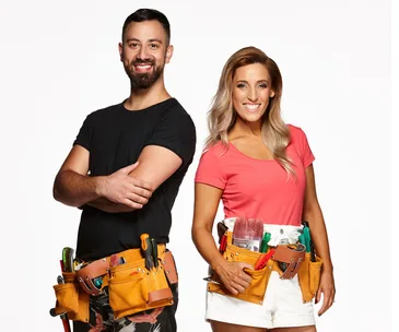 Two people with tool belts smiling at the camera against a white background.