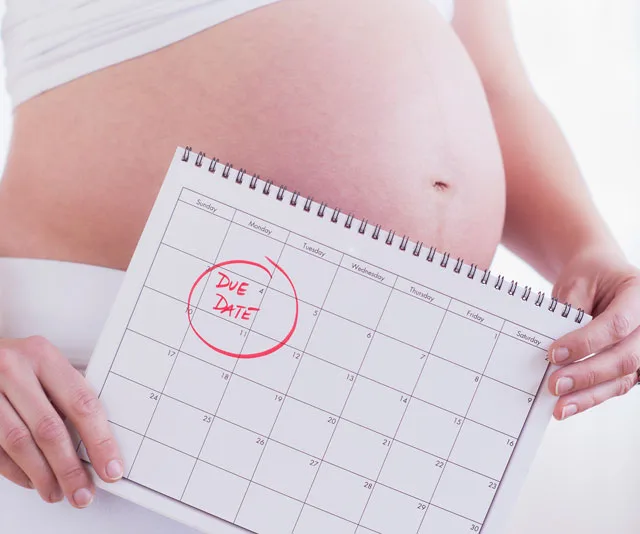 Pregnant woman holding calendar with "Due Date" circled in red.