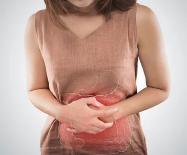 A woman clutching her stomach, illustrating digestive discomfort and showing an overlay of intestines.