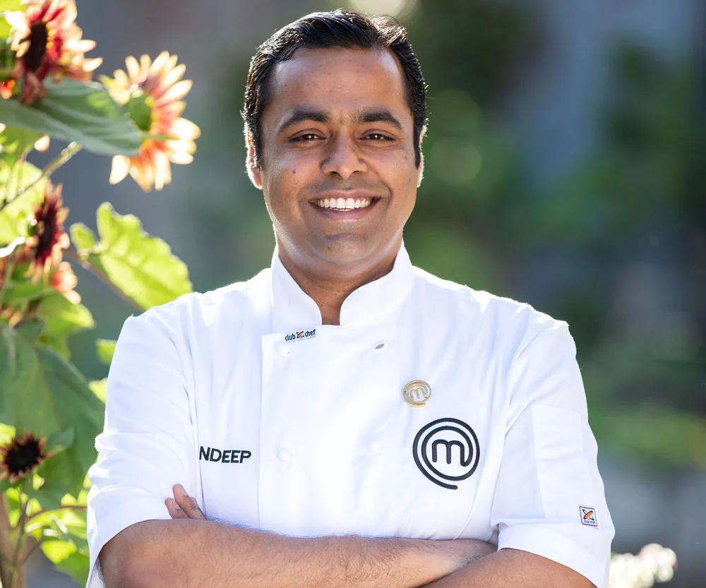 Sandeep in a MasterChef uniform smiling, standing outdoors near sunflowers.
