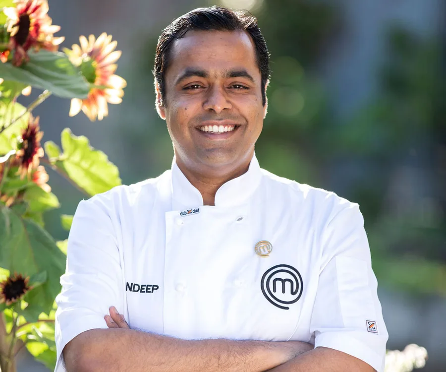 Sandeep in a MasterChef uniform smiling, standing outdoors near sunflowers.