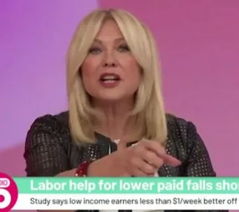 A person speaking on a TV show set, with a news ticker about labor help for lower income earners displayed below.