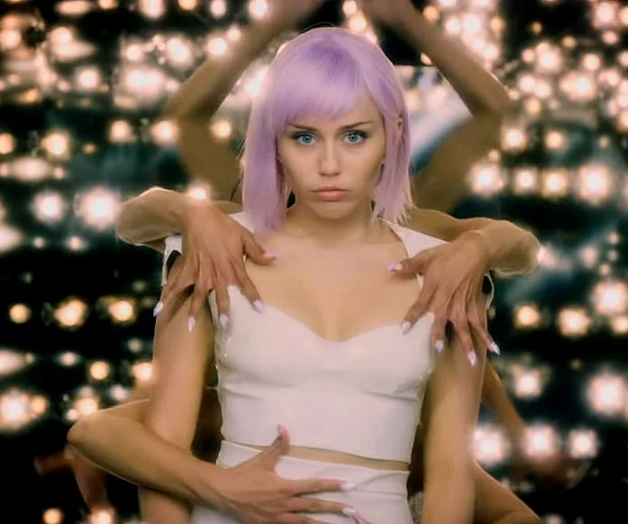 Ash with lavender hair surrounded by dancers' arms in a dazzling scene from Black Mirror Season 5.
