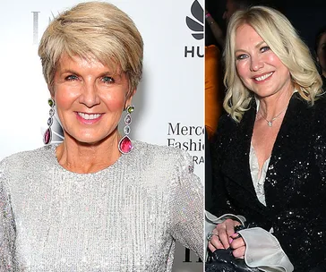 Two women smiling at a fashion event, one wearing a silver top, the other in a black outfit, both with earrings.