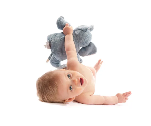 A smiling 5-month-old baby lies on their back, holding a blue plush elephant toy.