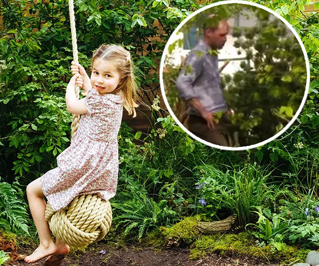 A young girl in a floral dress swings on a rope while a man is visible in a forested area in the background.