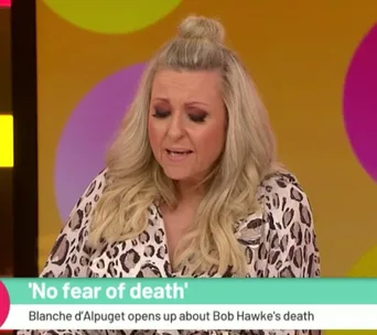 Blonde woman speaking with eyes closed on a daytime TV segment titled "No fear of death."