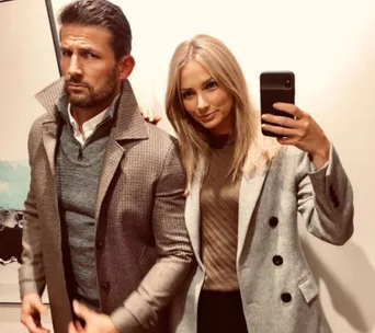 Couple taking a selfie in a mirror, both wearing stylish coats.