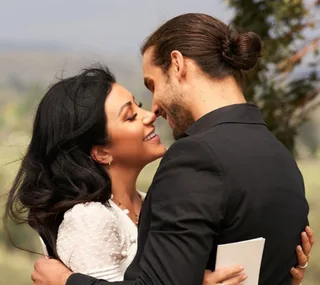 A couple embracing outdoors, smiling and gazing into each other's eyes lovingly.