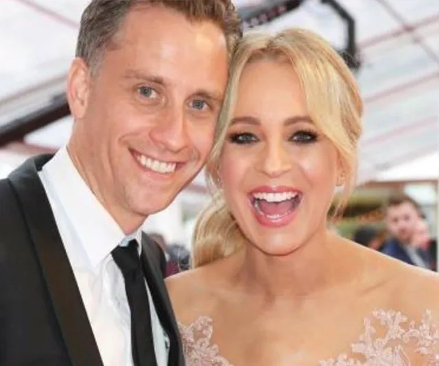 Two people smiling at a formal event, one wearing a suit and the other a lace dress.