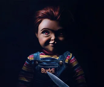 Close-up of a sinister doll in overalls with "Buddi" on the chest, holding a knife, from the "Child's Play" remake.