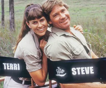 Couple in khaki attire sitting on chairs labeled "Terri" and "Steve" with "The Crocodile Hunter" logo, outdoors.