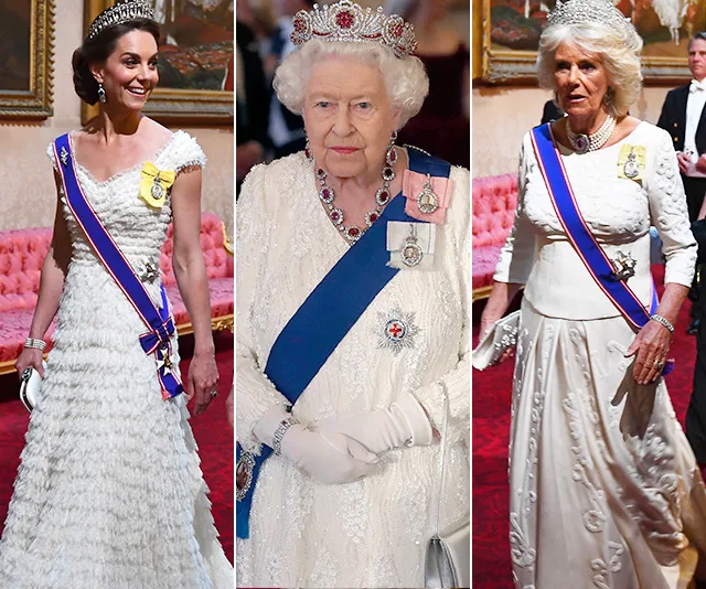 Three women in elegant white gowns with blue sashes and tiaras attend a state banquet.