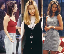Three women from Friends showcasing 90s fashion: Monica in jeans, Phoebe with a dress, and Rachel in a checkered dress.