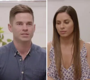 Man in a blue shirt and woman in a floral dress from "The Super Switch" are sitting and talking indoors.