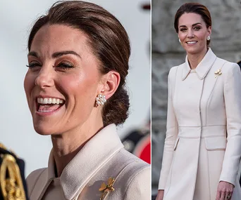 "Person in a cream coat, smiling in close-up and standing outdoors, wearing elegant pearl earrings."