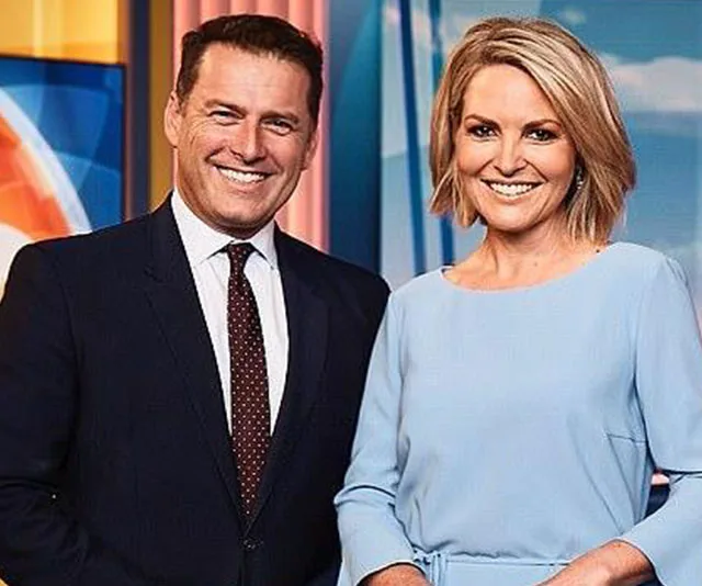 Two smiling TV presenters in professional attire on a colorful studio set.
