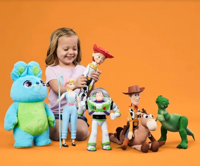 A child playing with Toy Story characters like Woody, Buzz, and Jessie against an orange background.