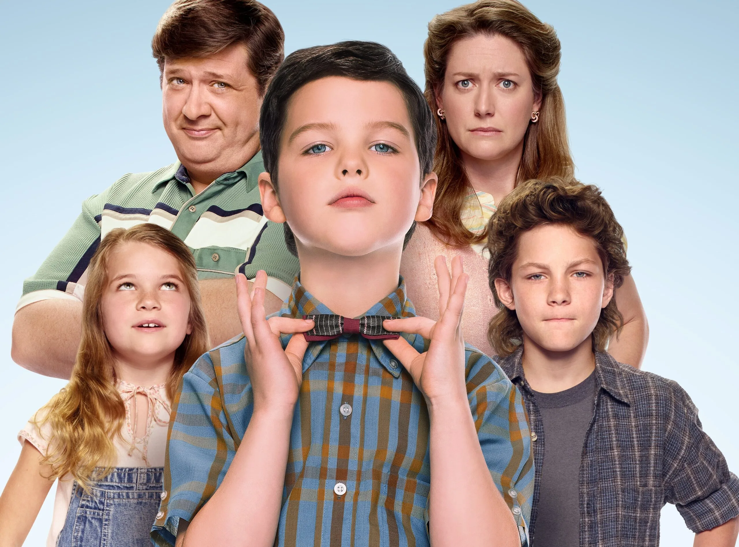 Cast of "Young Sheldon" in character, with Sheldon adjusting his bow tie, surrounded by family.