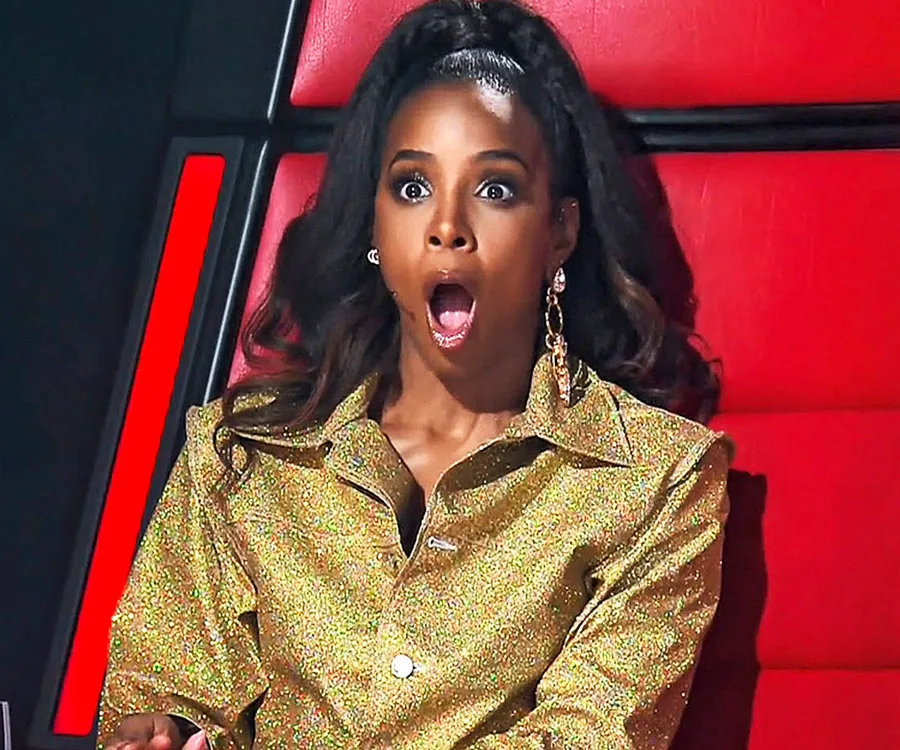 Judge on The Voice Australia, surprised in golden outfit, red chair background.