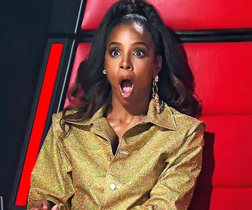 Judge on The Voice Australia, surprised in golden outfit, red chair background.