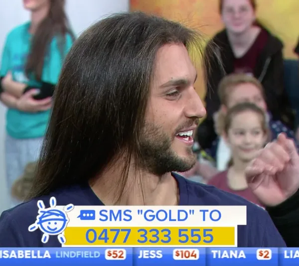 Man with long hair smiling, surrounded by people in a colorful studio setting, with donation info displayed below.