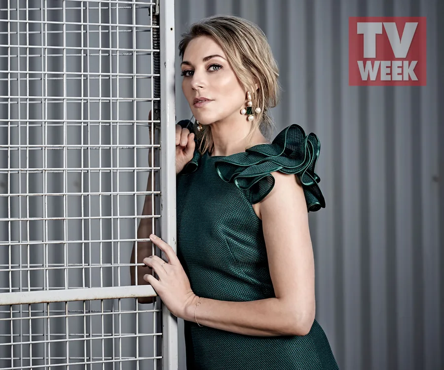 Woman in a green dress poses by a metal grid, with "TV WEEK" logo in the background.