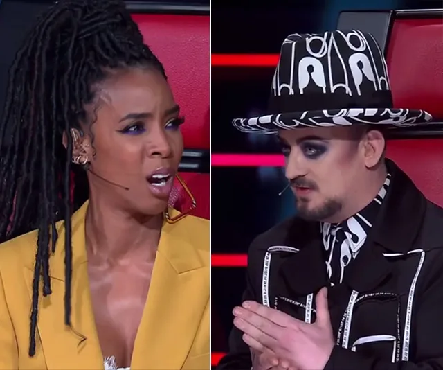 Two judges react during a segment of a talent show, one wearing a mustard jacket and the other in a patterned hat and jacket.