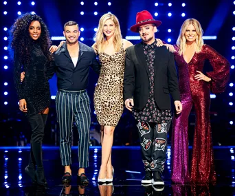 Five individuals stand together on a stage with illuminated background, dressed in vibrant and stylish outfits.
