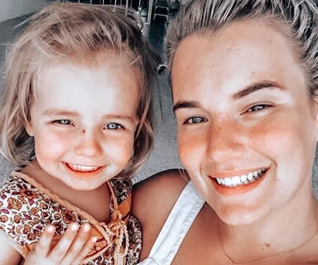 A smiling woman and child taking a close-up selfie indoors.