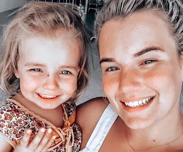 A smiling woman and child taking a close-up selfie indoors.
